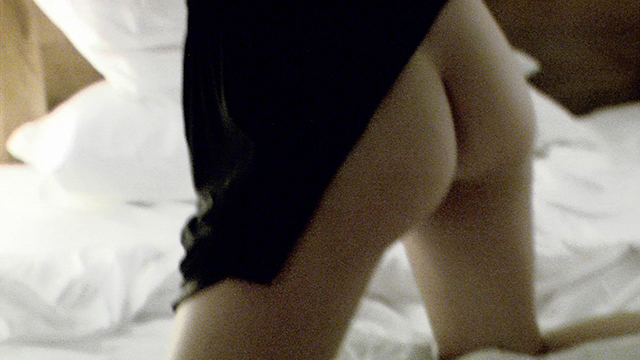 butt hotel bed Im Bett kniend entblößt Niki Blau ihren kleinen runden Po, indem sie ihr kurzes schwarzes Kleid hochzieht. Sie trägt keinen Slip.